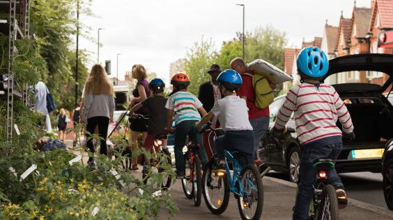 Kids on bikes being led by adults on sidewalk