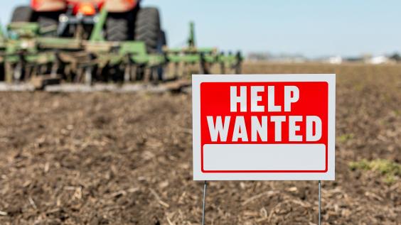 "Help wanted" sign superimposed on plowed land