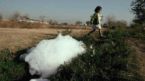 A girl walks by a polluted stream in Cuenavaca.