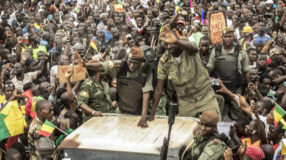 Members of the Malian junta wave as civilians gather to celebrate the overthrow of the president on Aug. 21, 2020.