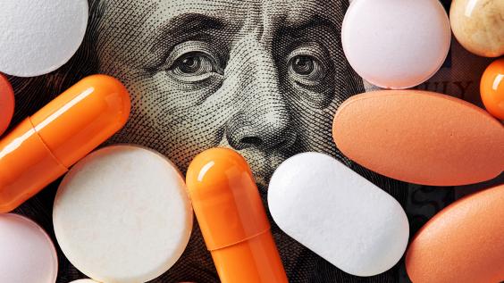 Capitalism and healthcare policy concept. Colorful medical pills cover Benjamin Franklin's face on one hundred American dollar bill. Macro top down view.