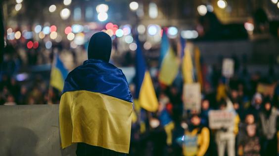 Person standing in crowd wearing Ukrainian flag
