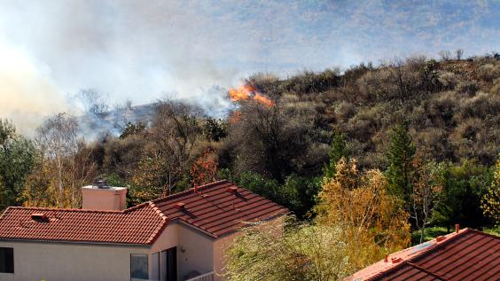 Wildfire erupts near houses on a hill