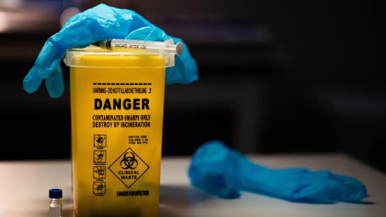 Gloves and syringe on top of sharps container