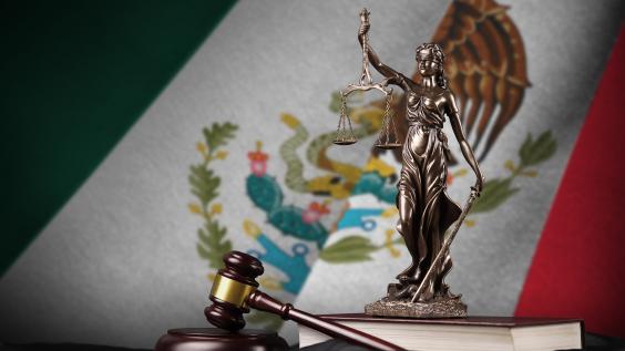 Mexico flag with statue of lady justice, constitution and judge hammer on black drapery. Concept of judgement.