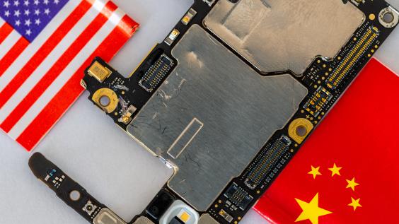 Micro chips and parts of a cellphone in between the American and Chinese national flags