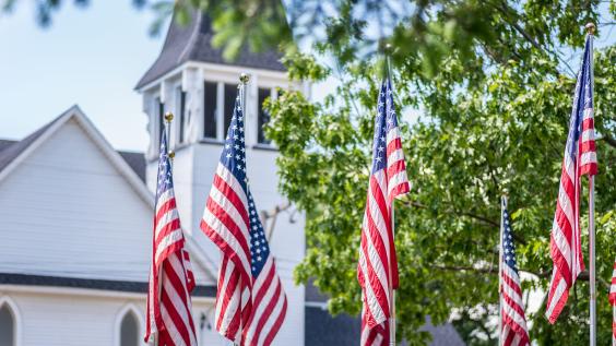 American flags waving outside old white church building