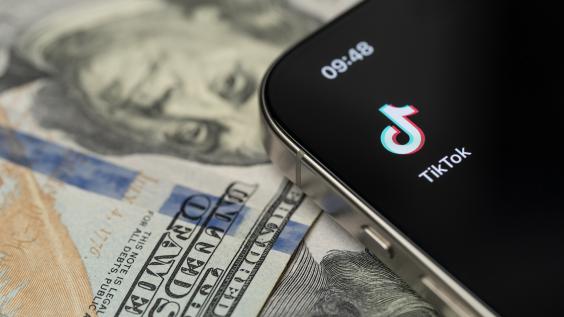 TikTok app on smartphone screen with dollar background