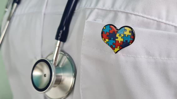 A Doctor Wearing a Stethoscope and a Puzzle Piece Heart Pin.