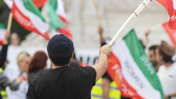 Man holding Iranian flag at women’s rights protest