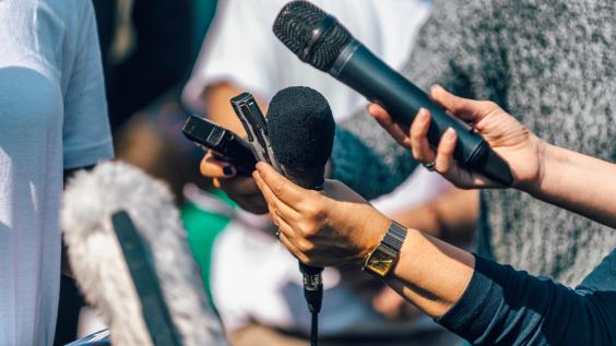 Reporters hold up microphones