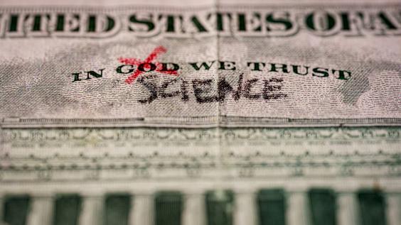 Word God crossed out and replaced by science on a US dollar bill. 