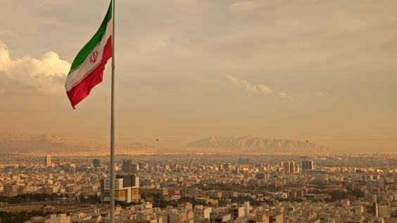 Iran Flag in the Wind Above Skyline of Tehran 