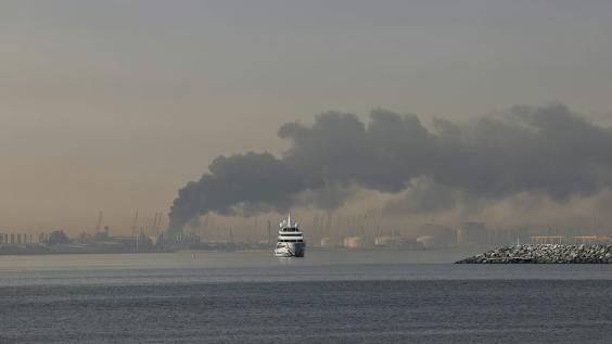 A yacht sails past a plume of smoke rising from the port of Jebel Ali following a reported Iranian strike in Dubai on March 1, 2026.