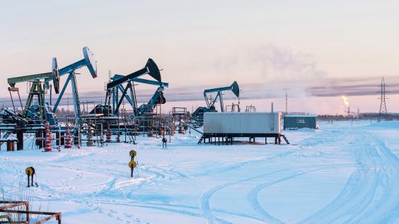 Oil Field. Winter industrial landscape with an oil pump and torch in the background. 