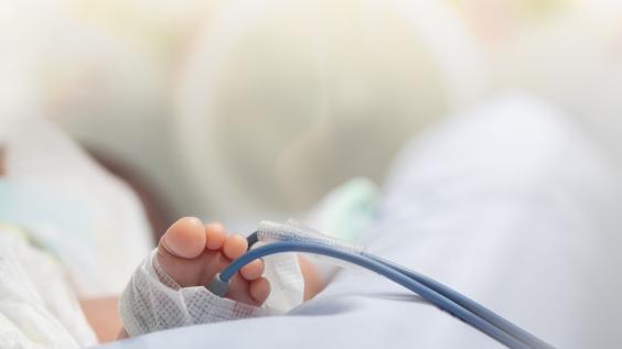 Infant or newborn baby feet with pulse oximeter for determine oxygen saturation in baby's blood, in incubator at intensive room care in the hospital after delivery.