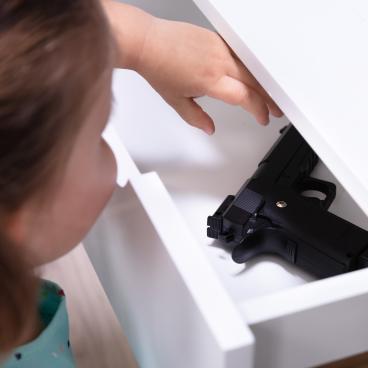 Small child reaches into drawer with firearm