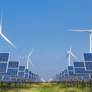 Windmills and solar panels in a grass field.
