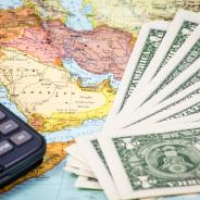 Money and a calculator rest on top of a map of the Middle East.