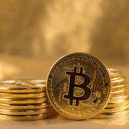 A Bitcoin leans against two stacks of Bitcoins.
