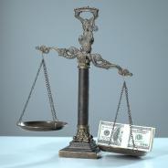 Money weighs down a balance scale.
