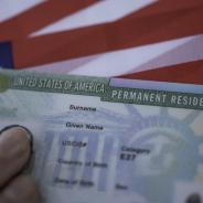 A permanent resident card rests on a U.S. flag.