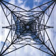 This photo shows an upward view of a transmission tower.