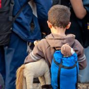A refugee boy holds a stuffed animal.