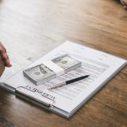 Wad of cash on top of a contract