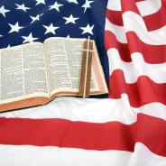 A Bible and the Christian cross on top of an American Flag.