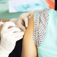 A woman receives a vaccine in her left arm.
