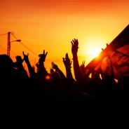 Hands raise up against a sunset.