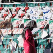 Woman in Iran stands in front of election posters