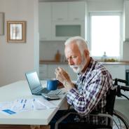 An elderly man in a wheelchair reviews billing statements.