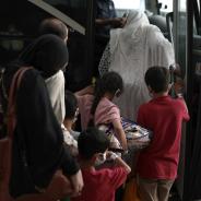 A family of Afghan refugees board a bus.