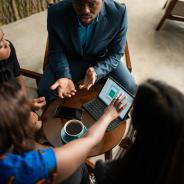 Four people discussing business around a table with coffee.