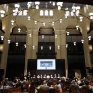 Participants gather at round tables in a large room to hear from a panel of experts
