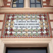 Tile mosaic over an entrance to Baker Hall that reads "A Bridge Between the World of Ideas and the World of Action"