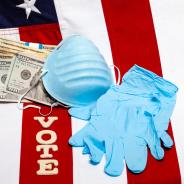 A mask, gloves, money, and letters spelling "vote" lie on a flag of the United States.