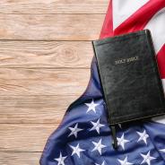 Holy Bible and American flag on wooden background