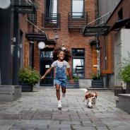 Child running alongside dog in city environment