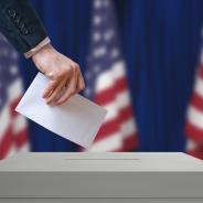 Voter holds envelope in hand above vote ballot