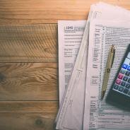 tax forms on table with calculator and pen on top