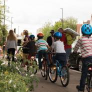 Kids on bikes being led by adults on sidewalk