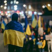 Person standing in crowd wearing Ukrainian flag