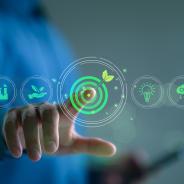 Business person touches a virtual screen displaying icons like renewable energy, co2 emissions reduction, green production, waste recycling, and solar power.