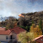 Wildfire erupts near houses on a hill