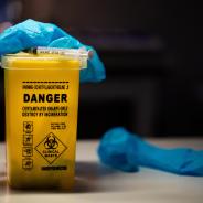 Gloves and syringe on top of sharps container
