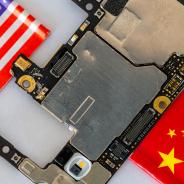 Micro chips and parts of a cellphone in between the American and Chinese national flags