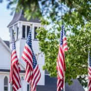 American flags waving outside old white church building